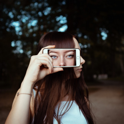 woman holding smartphone with background of woman s face 3887990